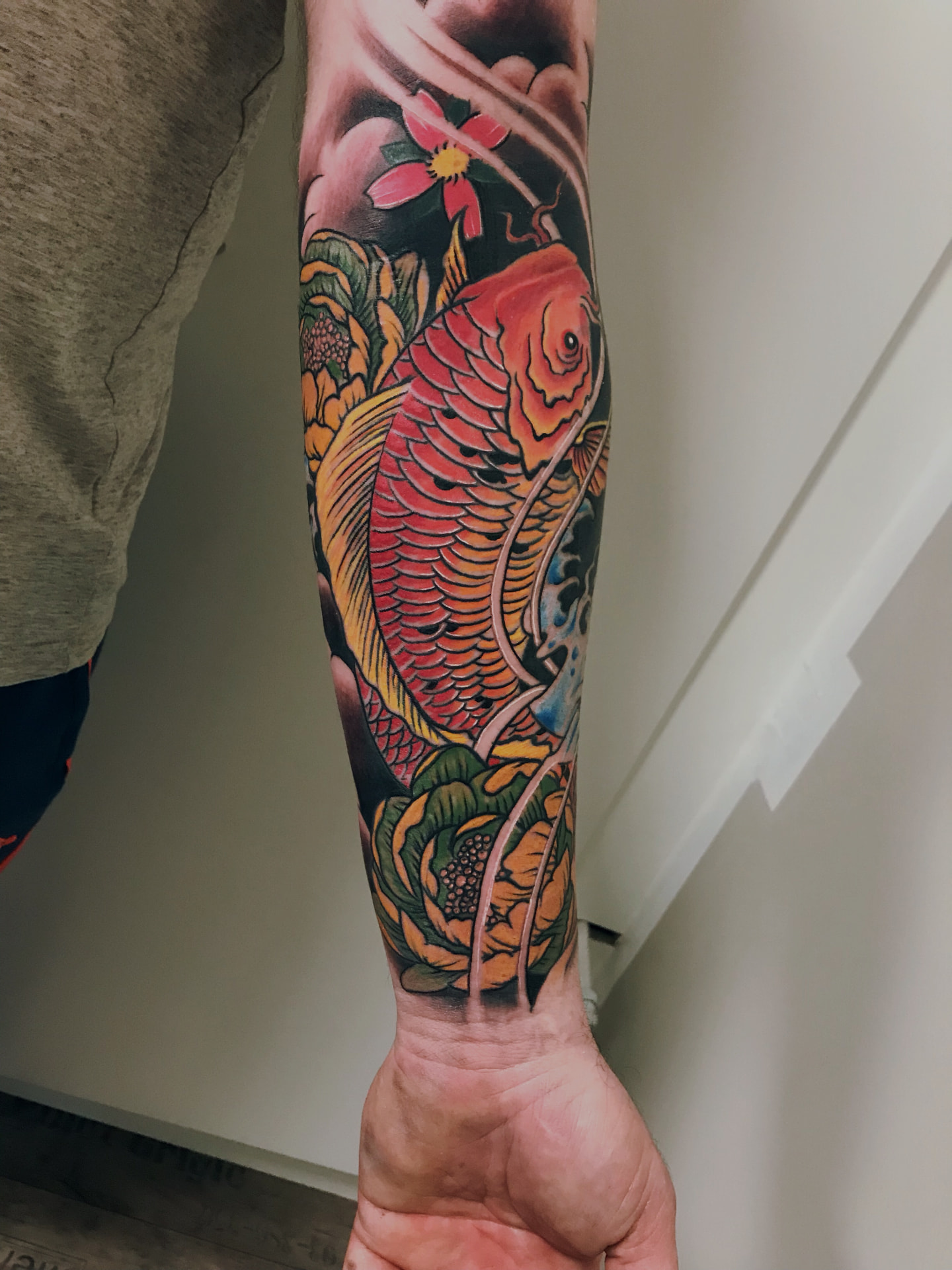 Japansk inspireret farvetatovering med koifisk, peoner og kirsebærblomst på underarm