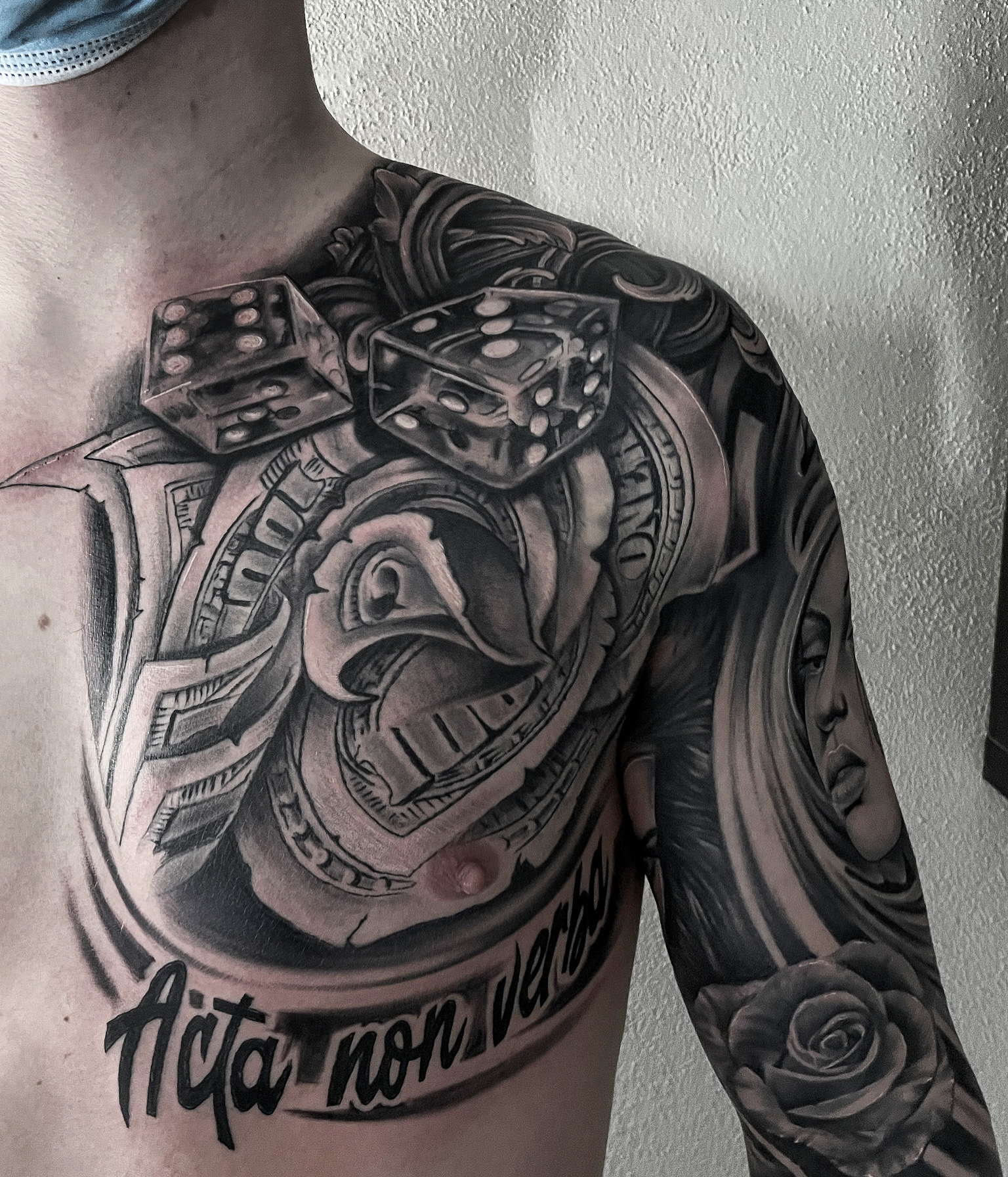Black and grey chicano-brysttatovering med terninger, pengesedler, rose og Acta non verba