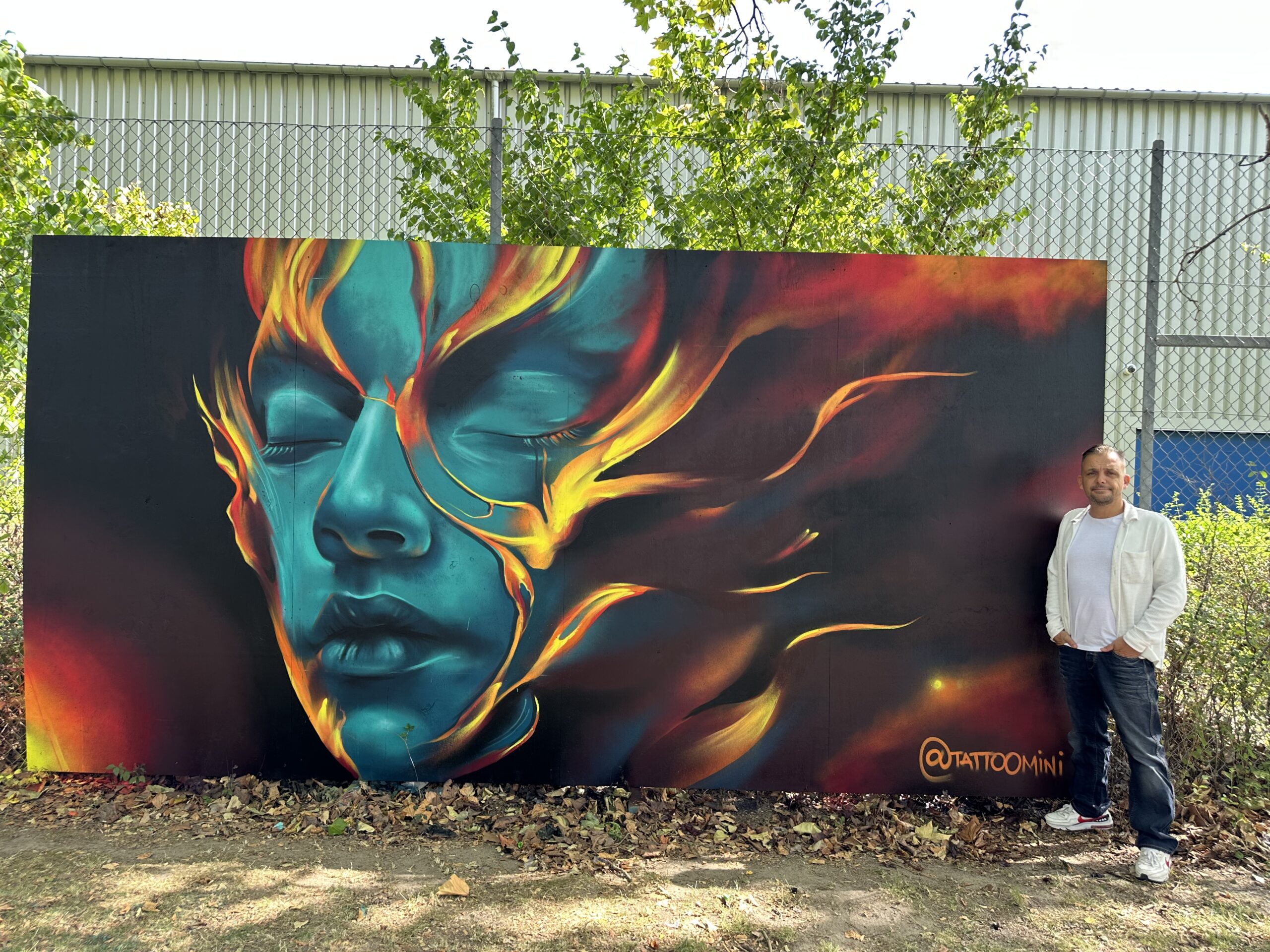 Streetart art portræt af kvindeansigt i blågrønt.og orange ild ,detaljerig graffiti malet på væg. Glostrup streetart festival, af Tattoo Mini