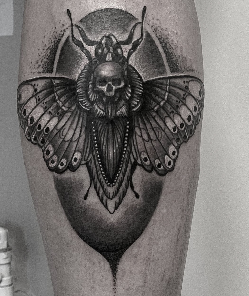 Black and grey tatovering af dødningehovedsværmer med kranie på underben