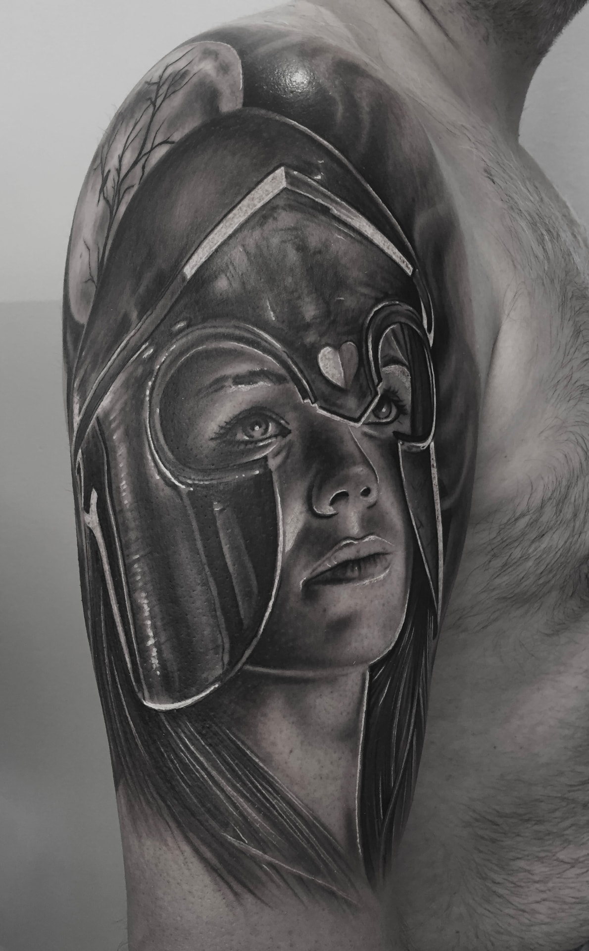 Black and grey tatovering af kvindelig kriger med spartansk hjelm på skulder
