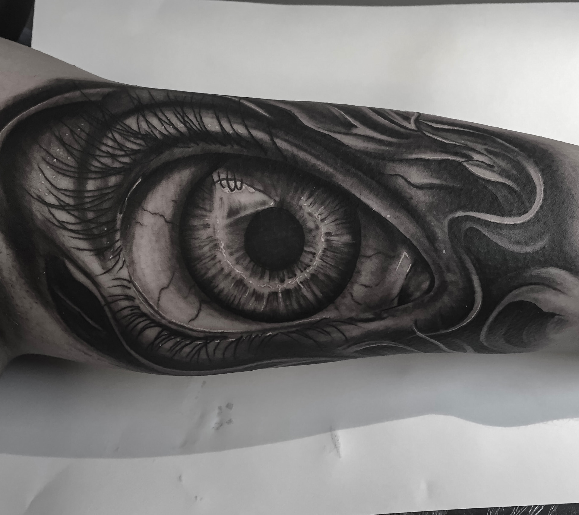 Black and grey tatovering af stort realistisk øje med biomekaniske detaljer på underarm