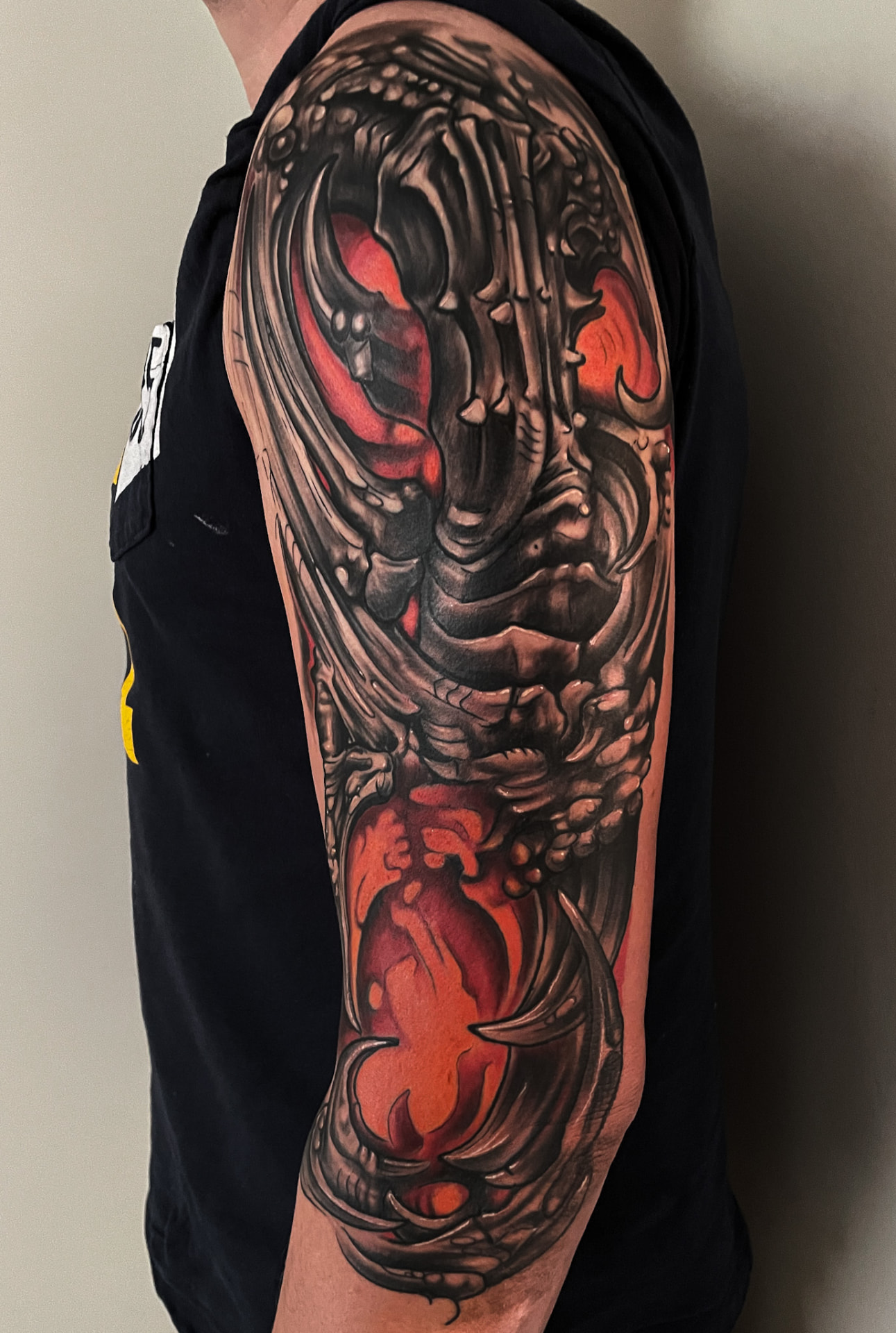 Biomekanisk tatovering i sort, grå og rød på overarm