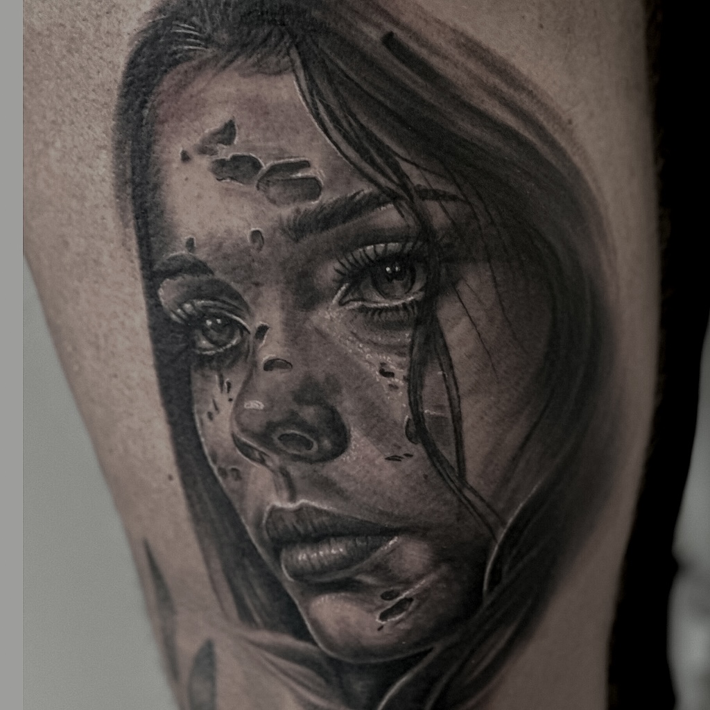 Black and grey portræt-tatovering af kvindeansigt på lår