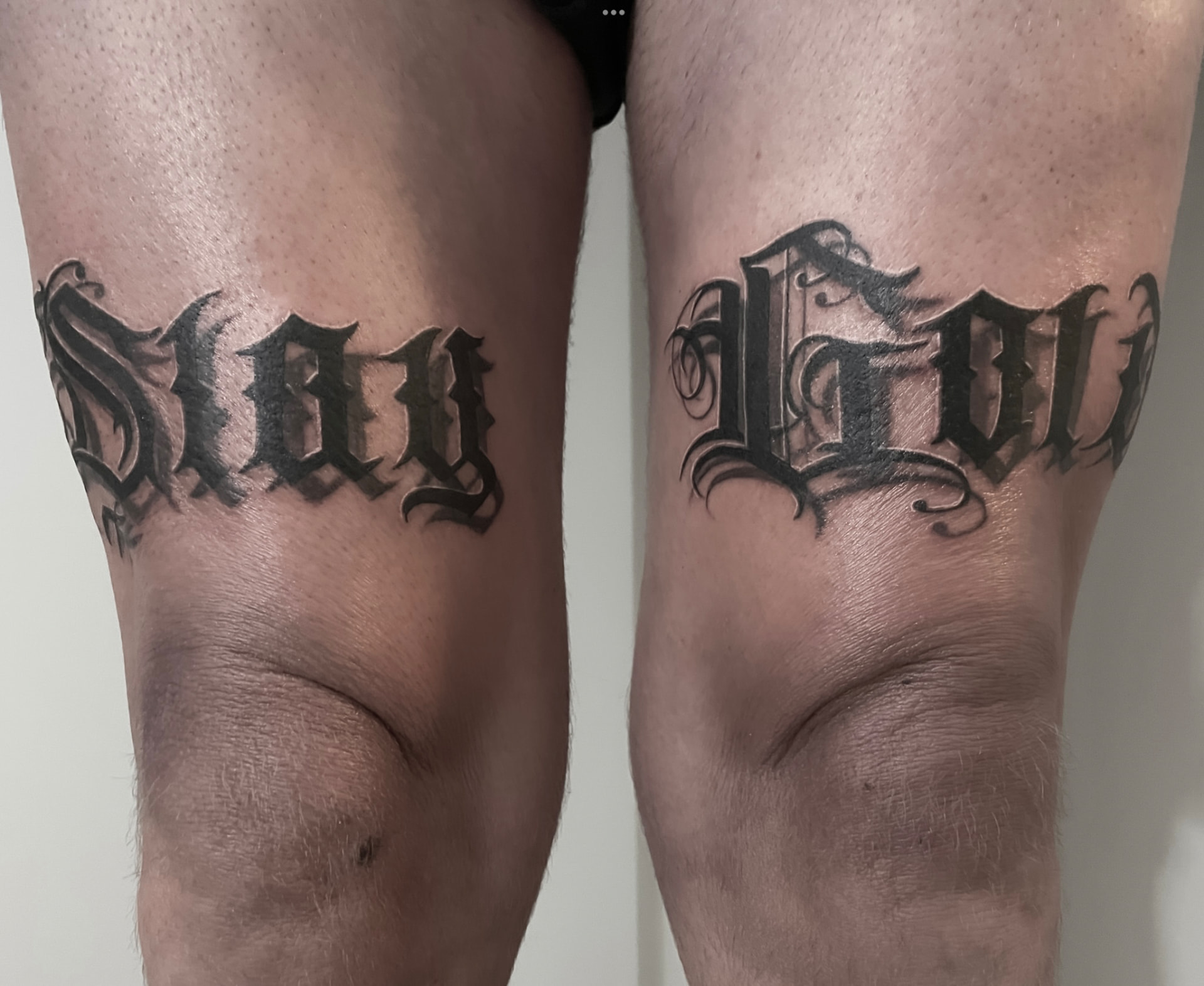 Gotisk lettering-tatovering Stay Gold hen over begge lår i sort