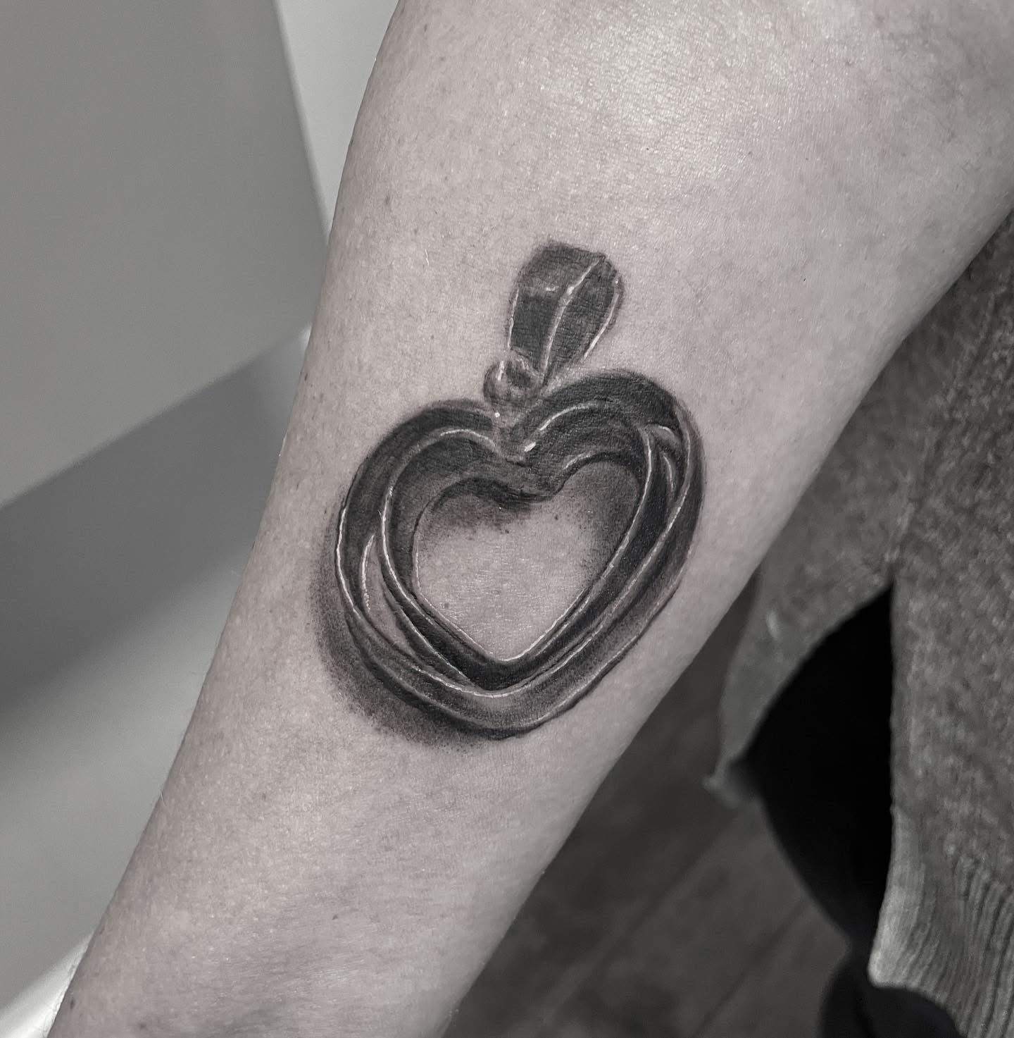 Realistisk black and grey hjertevedhæng som smykke-tatovering på underarm