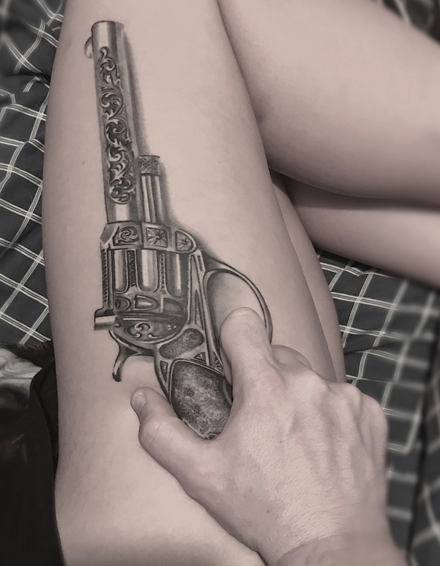 Black and grey tatovering af graveret revolver i realistisk stil på underarm