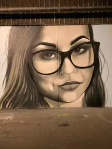 Vægmaleri af kvinde med briller og markerede øjenbryn