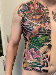 Farverig japansk tatovering med hannya maske, koi fisk og lotusblomster fra Tattoo Mini København