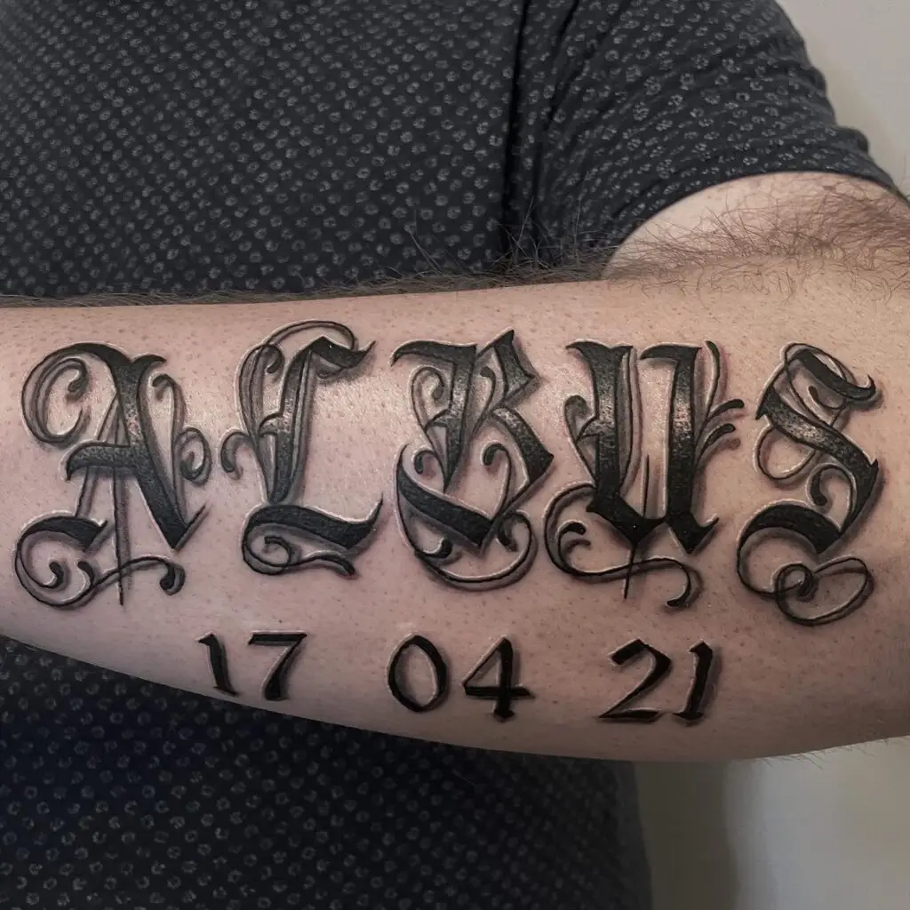 Tatovering med navnet ALBUS og datoen 17-04-21 i gotisk skrift af Tattoo Mini