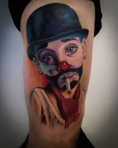 Farverig klovnetatovering med sort hat og cigaret – realistisk og karikeret stil, fra Tattoo Mini