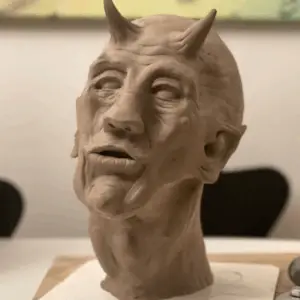 Håndlavet skulptur i ler – portræt af djævlen med horn og udtryksfuldt ansigt.
