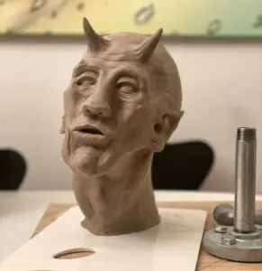 Lerskulptur af mandlig fantasifigur med horn og udtryksfuldt ansigt