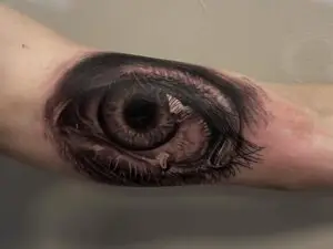 Hyperrealistisk tatovering af et øje på underarmen, med ekstreme detaljer i iris og hudstruktur.