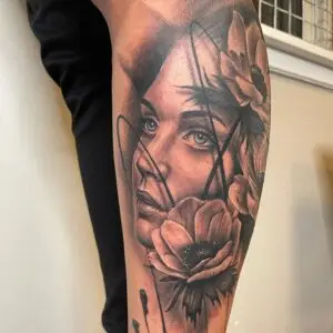 Realistisk tatovering af kvindeportræt med blomster og grafiske streger – sort/grå med soft shading.fra Tattoo Mini