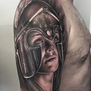 Hyperrealistisk tatovering af kvindelig kriger med hjelm, udført i sort/grå med dramatiske lysreflekser.Freya