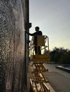Streetart-kunstner sprayer vægmaleri fra lift i solnedgang
