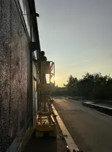 Kunstner arbejder på stor gavlmaleri i lift ved solnedgang. Musikon roskilde