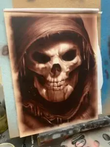 Dark-toned artwork on clayboard of a hooded skull figure with empty eye sockets and a sinister grin, airbrushed in sepia tones for a haunting effect.