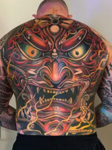 Farverig japansk dæmondesign-tatovering over hele ryggen