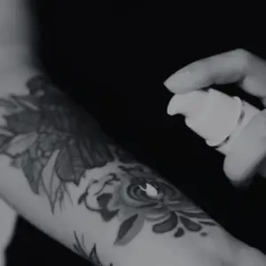 Påføring af aftercare-spray på frisk tatovering for at beskytte huden – Tattoo Mini København
