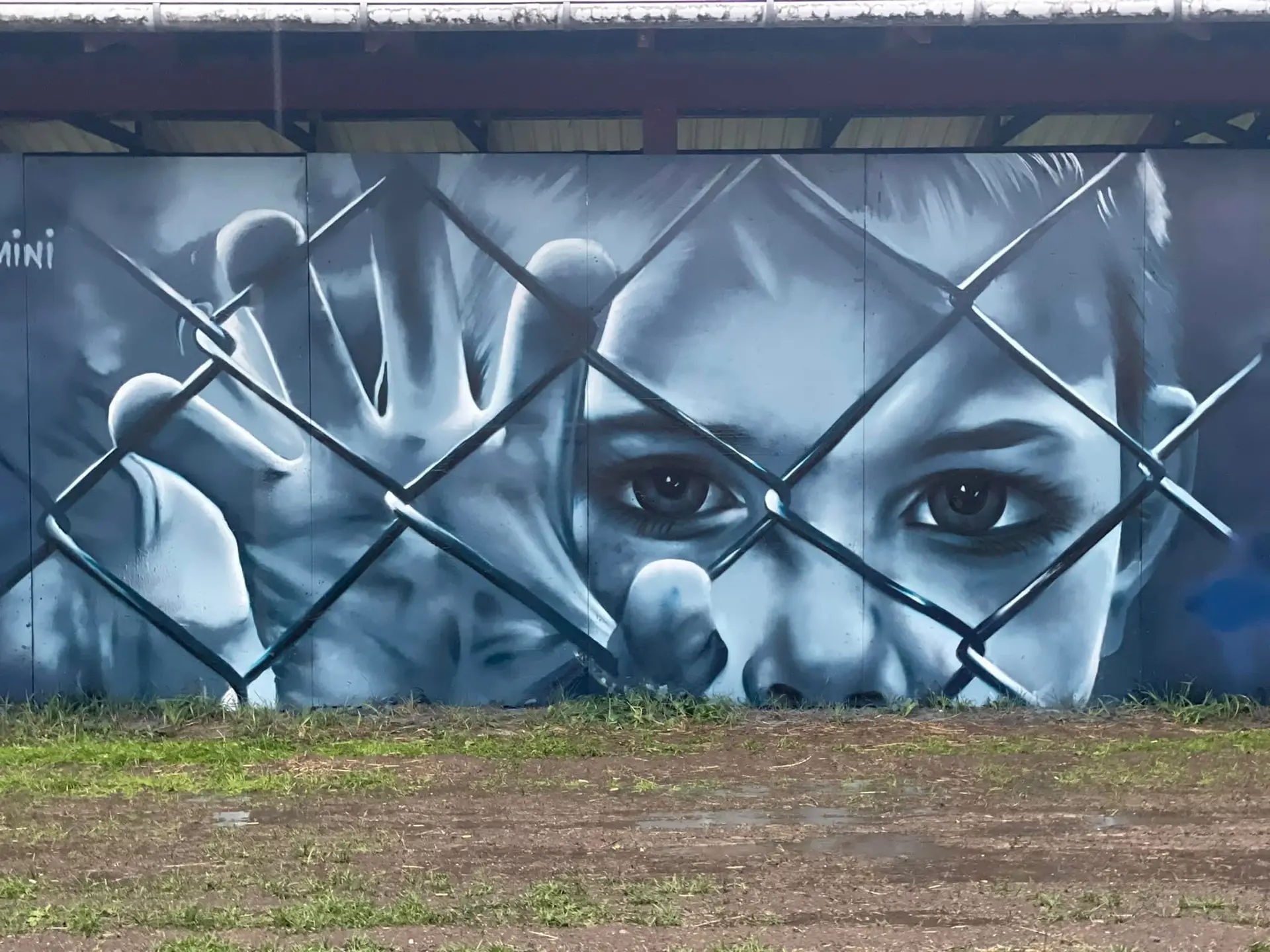 Realistisk streetart af barn bag hegn – muralmaleri af Tattoo Mini københavn