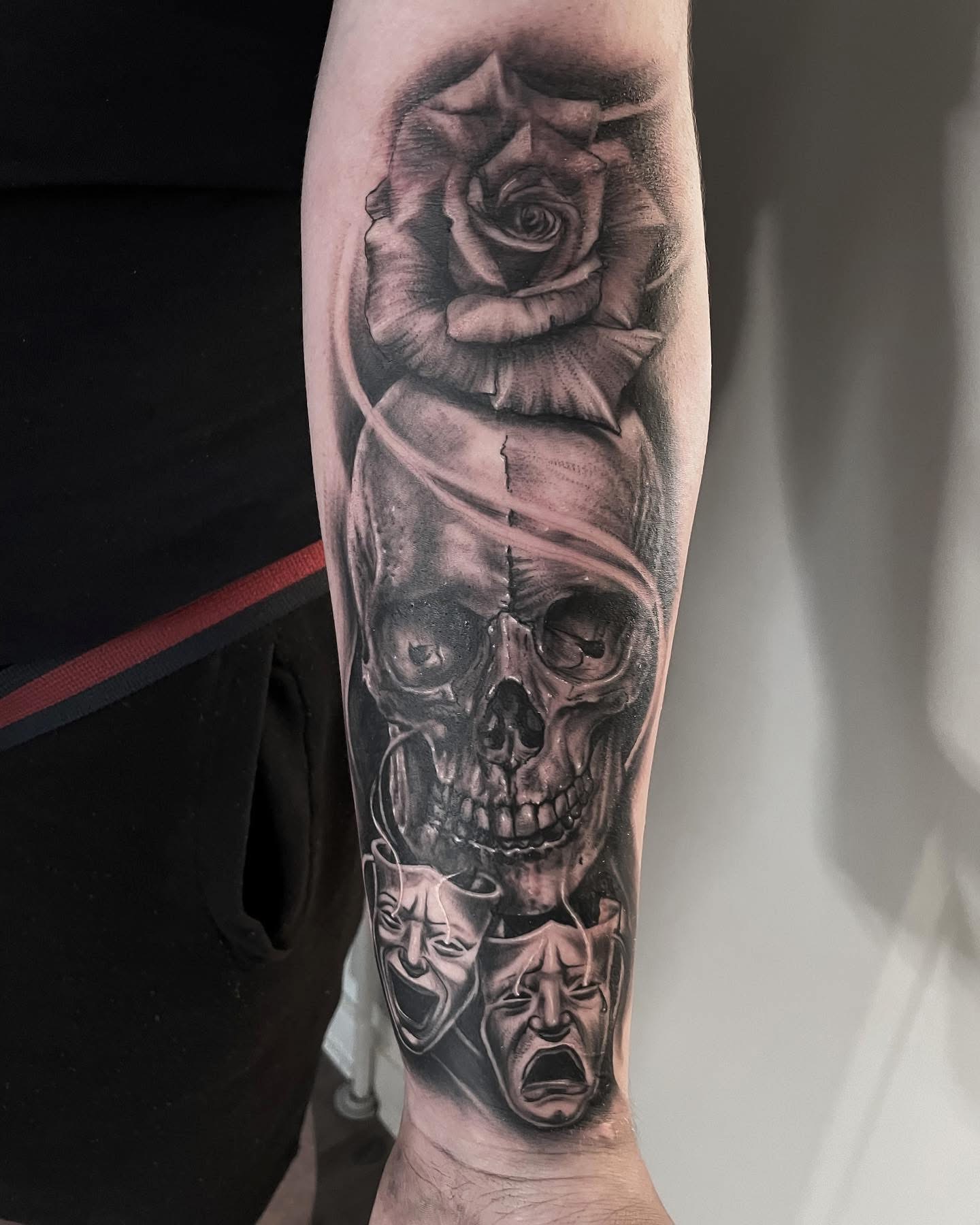 Realistisk black and grey tattoo med kranie, rose og teatermasker på underarm udført af Tattoomini i København