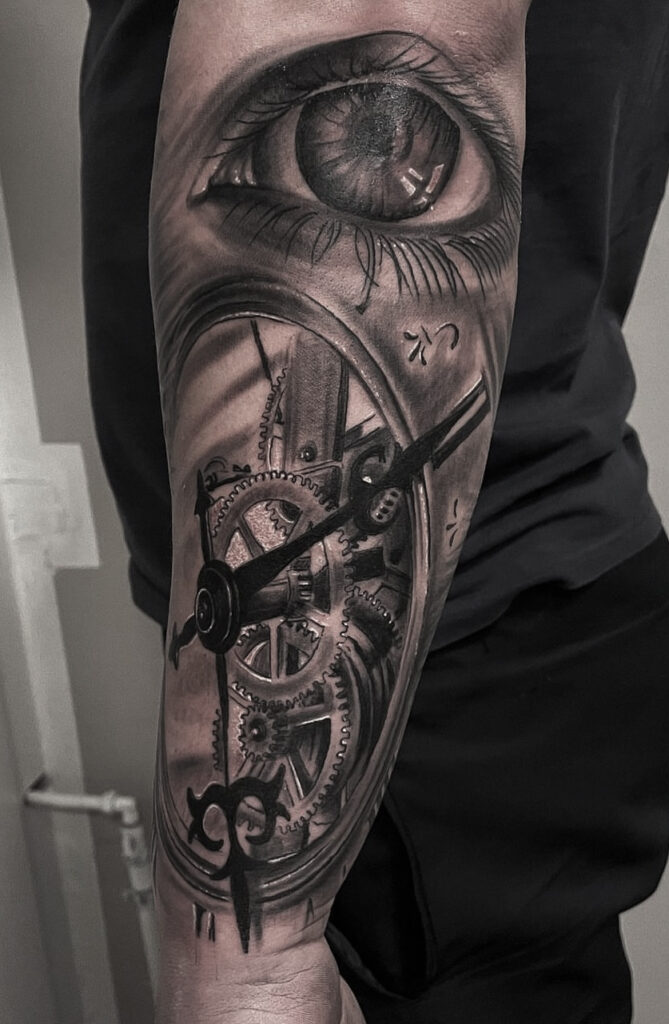 Realistisk underarm tattoo med stort øje, urværk og mekaniske detaljer i black and grey stil