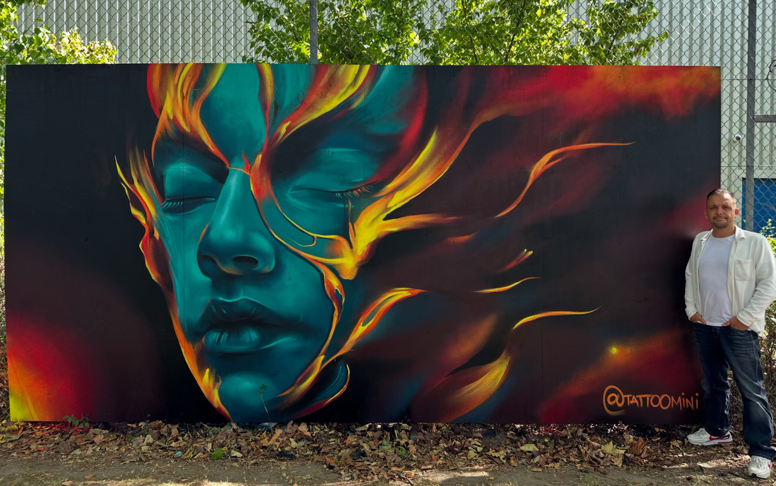 Farverigt street art-maleri af ansigt med flammer i blå og orange