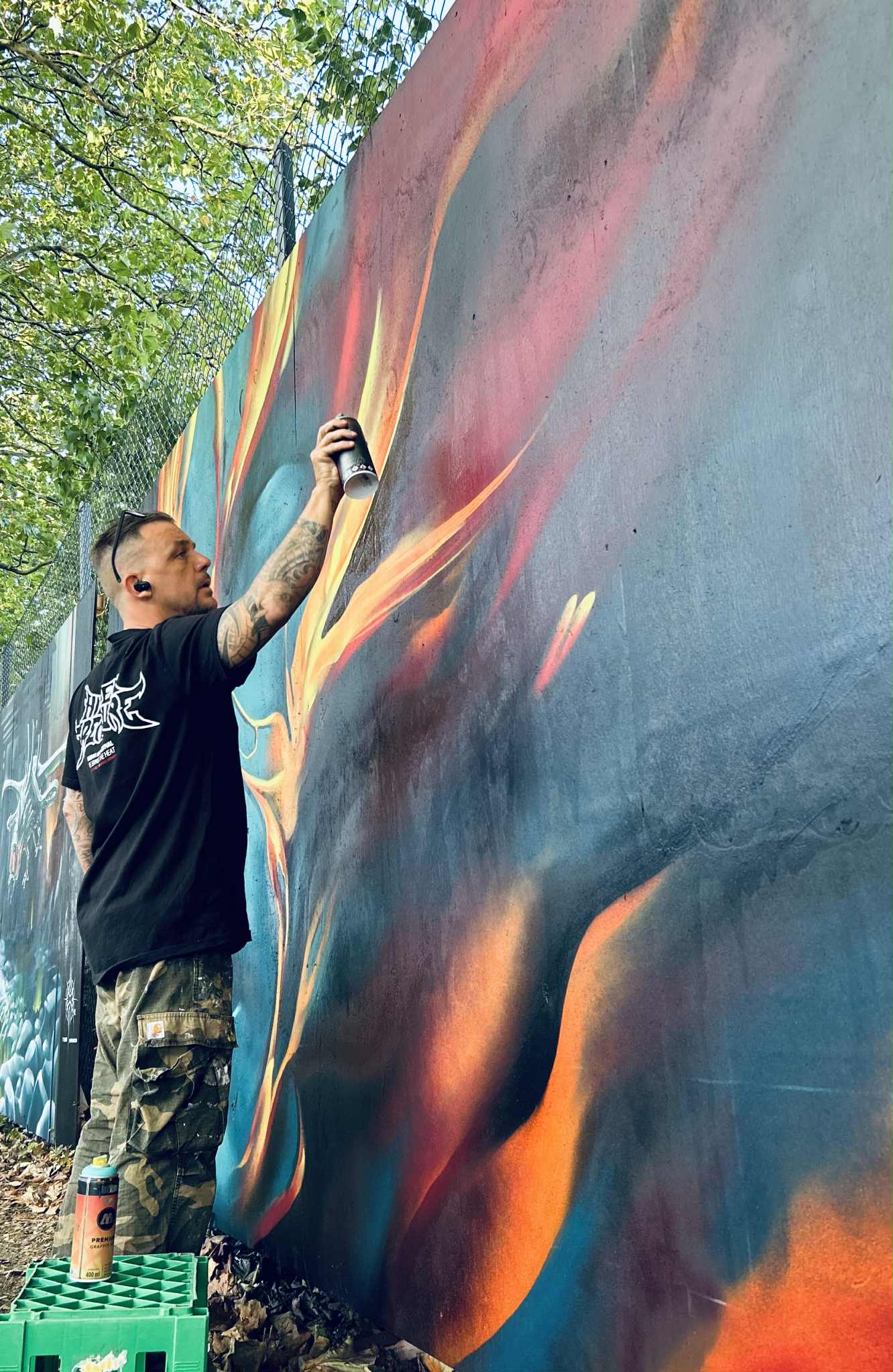Tatovør og street art-kunstner i gang med vægmaleri fra lift